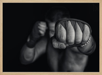A dramatic black and white close-up photograph of a boxer's wrapped fist punching towards the camera. The fighter's body and other fist are blurred in the background, creating a powerful and intense mood. Print