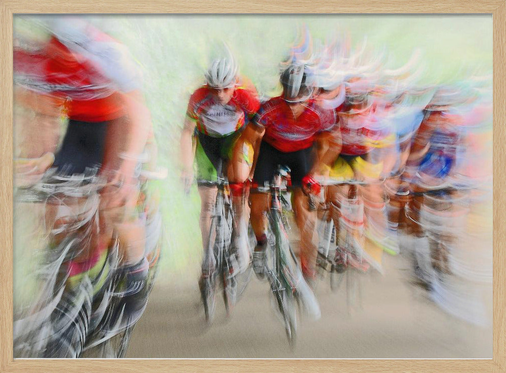 An abstract photograph of a group of cyclists in a race, captured with motion blur to create a dynamic sense of speed. The riders' red jerseys and the green background are streaked together, with a silver frame surrounding the image. Artwork