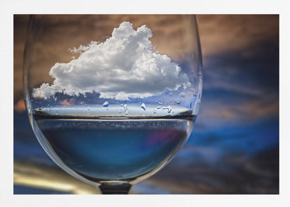 A surreal close-up of a wine glass holding blue liquid and a single white cloud, with water droplets on the glass, set against a blurred background and enclosed in a silver frame. Print