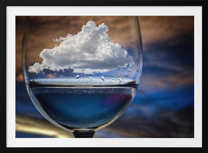 A surreal close-up of a wine glass holding blue liquid and a single white cloud, with water droplets on the glass, set against a blurred background and enclosed in a silver frame. Print