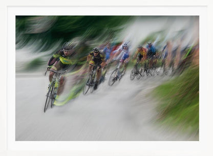 A dynamic, motion-blurred photograph of a group of cyclists in a race, captured with a slow shutter speed to create streaks of color and a sense of high speed. The lead cyclist in a yellow and black jersey is the most defined figure, leaning into a turn on a grey road flanked by blurry green foliage. The entire image is enclosed in a silver frame. Decor