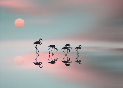 A serene artwork of five black flamingo silhouettes wading in calm water, their reflections mirrored below them. The background is a soft, blurred gradient of pastel pink and teal, with a pale pink sun low in the sky, creating a tranquil sunset scene. Poster