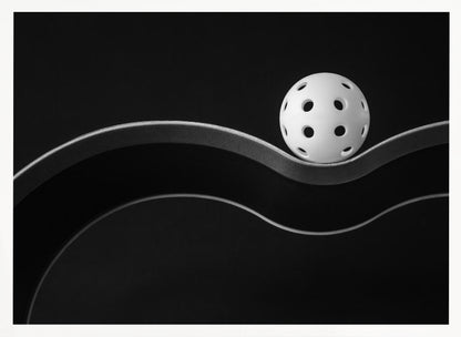 A minimalist black and white photograph of a white pickleball resting perfectly balanced on a thick, wavy, textured line against a solid black background. Below it, a thin white line mimics the curve. The entire piece is framed in silver. Poster