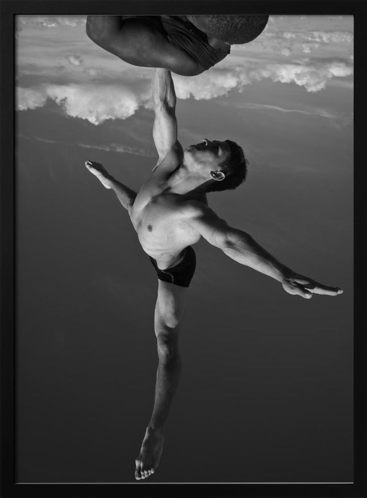 A surreal black and white photograph of two male acrobats. One man, in a graceful dance-like pose balancing on one leg, holds another man aloft with a single outstretched arm. The man being held is upside down against a backdrop of clouds, creating a gravity-defying and artistic illusion. Print