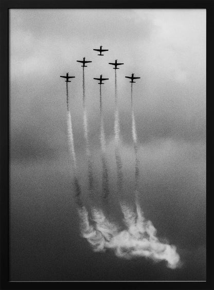A grainy black and white photo of six airplanes flying in a V-formation against a cloudy sky. Each plane leaves a long, white smoke trail that billows at the bottom of the frame. The image is presented within a black border. Print