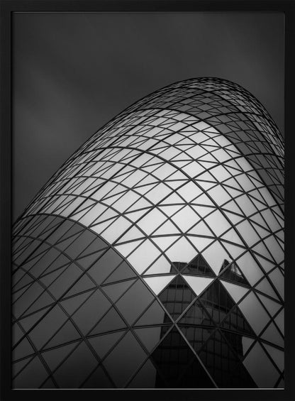 A framed, low-angle, black and white photograph of the curved, glass-paneled facade of a modern skyscraper, creating a dynamic pattern of reflective diamonds against a dark, moody sky. Artwork
