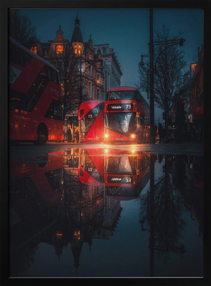 A moody, low-angle photograph of a wet London street at dusk, with a vibrant red double-decker bus reflected perfectly in a large puddle in the foreground. Print