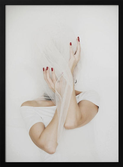 A minimalist photograph of a person in a white t-shirt against a white background, their face hidden by a sheer white veil. Their hands, adorned with bright red nail polish, frame the veiled face in an expressive pose. Wall Art