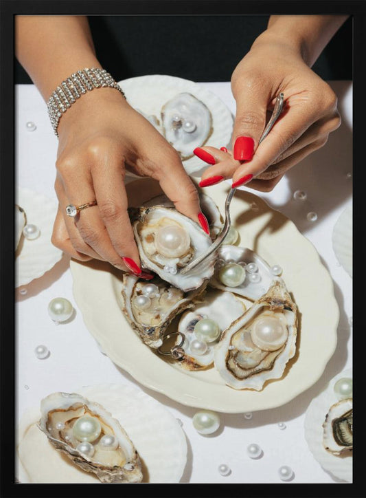 A close-up overhead shot of a woman's hands with vibrant red nails and elegant jewelry, using a fork to lift a large pearl from an oyster shell on a white plate. The plate and the surrounding white surface are adorned with numerous oysters filled with pearls of varying sizes, creating a luxurious and surreal scene. Print