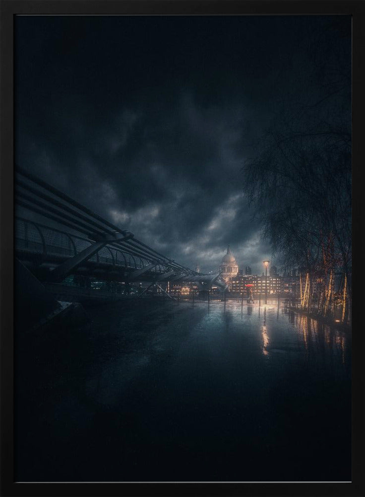 A moody, atmospheric night photograph of London, featuring the Millennium Bridge stretching across a wet surface towards the illuminated St. Paul's Cathedral under a dark, stormy sky. City lights reflect on the wet ground, and trees with warm lights line the right side of the frame. Artwork