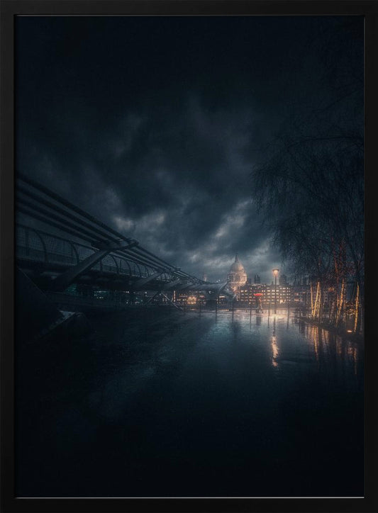 A moody, atmospheric night photograph of London, featuring the Millennium Bridge stretching across a wet surface towards the illuminated St. Paul's Cathedral under a dark, stormy sky. City lights reflect on the wet ground, and trees with warm lights line the right side of the frame. Artwork