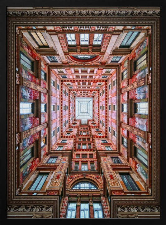 A symmetrical, worm's-eye view looking up through the center of an ornate, multi-story courtyard. The red and gold walls are covered in intricate details and frescoes, receding into the distance towards a square glass skylight. The entire artwork is presented within a decorative dark brown frame. Artwork