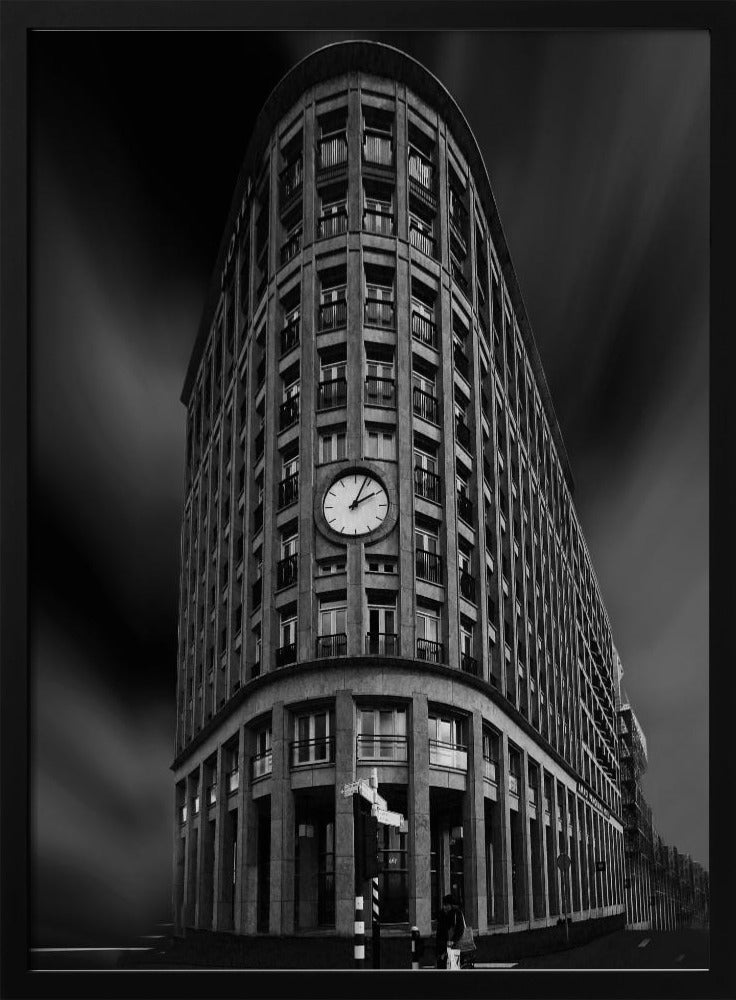 A dramatic low-angle, black and white photograph of a large, curved corner building with a prominent clock on its facade. The sky is dark with a motion blur effect, making the building appear grand and imposing. Artwork