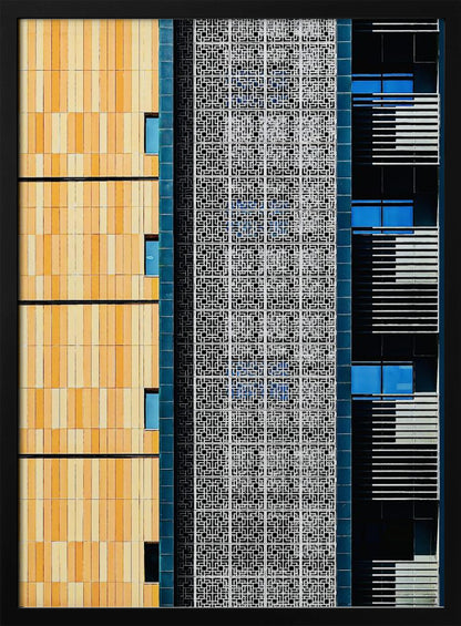 A vertical abstract architectural photograph showcasing the facade of a modern building, featuring a contrast of textures and colors: warm yellow vertical tiles on the left, an intricate white geometric screen in the center, and a dark section with vibrant blue windows on the right. Print