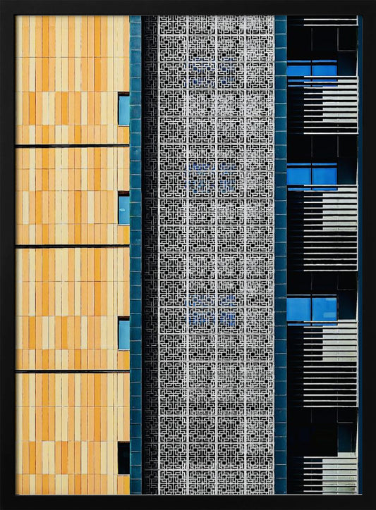 A vertical abstract architectural photograph showcasing the facade of a modern building, featuring a contrast of textures and colors: warm yellow vertical tiles on the left, an intricate white geometric screen in the center, and a dark section with vibrant blue windows on the right. Print