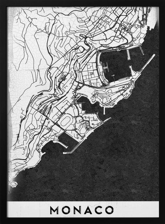 A modern black and white map of Monaco, presented as a framed poster. The map details the city's streets and coastline in black lines on a white background, while the sea is depicted in a solid, textured black. The title 'MONACO' is at the bottom in a bold, white band. Poster