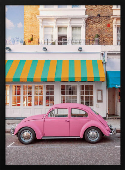 A vibrant, eye-level photograph of a vintage pink Volkswagen Beetle parked on a city street in front of a charming white storefront with a bold yellow and teal striped awning. Wall Art