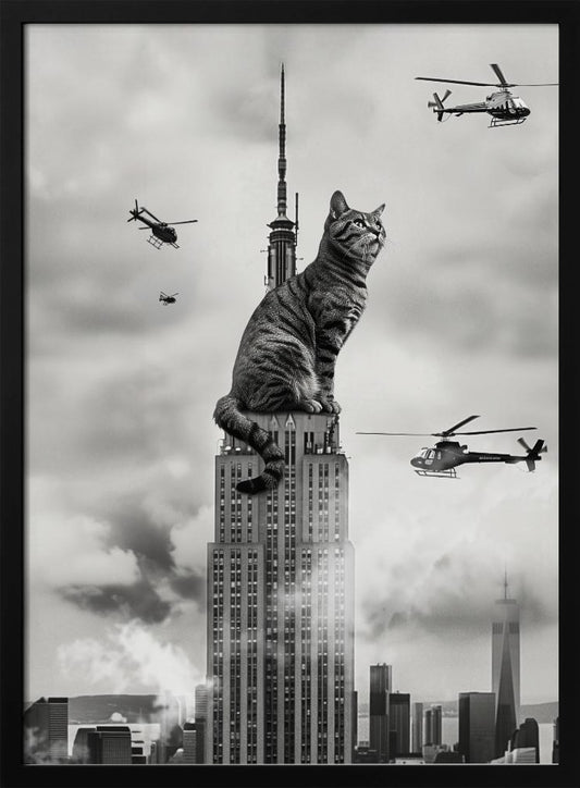 A surreal black and white image depicting a giant tabby cat sitting on top of the Empire State Building, similar to King Kong. Helicopters fly around the colossal cat against a cloudy New York City skyline. Decor