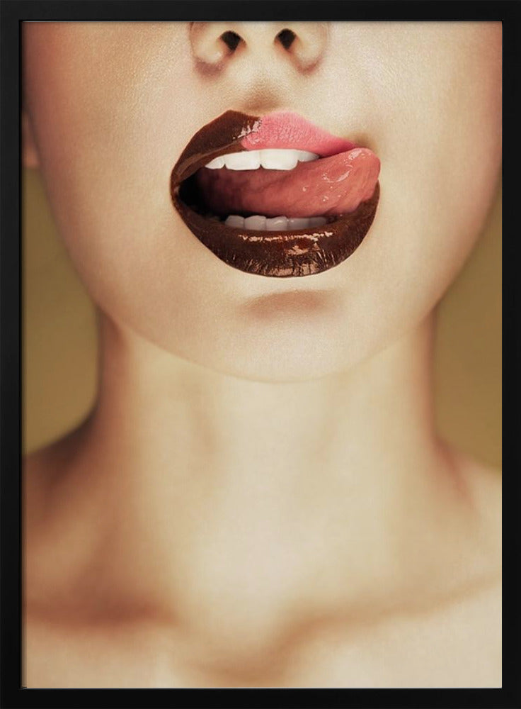 A close-up photograph of a woman's mouth with two-toned lipstick. The lips are mostly covered in glossy dark brown, with the upper right section in light pink. Her tongue is out, licking the pink part of her lip, revealing her white teeth. Print