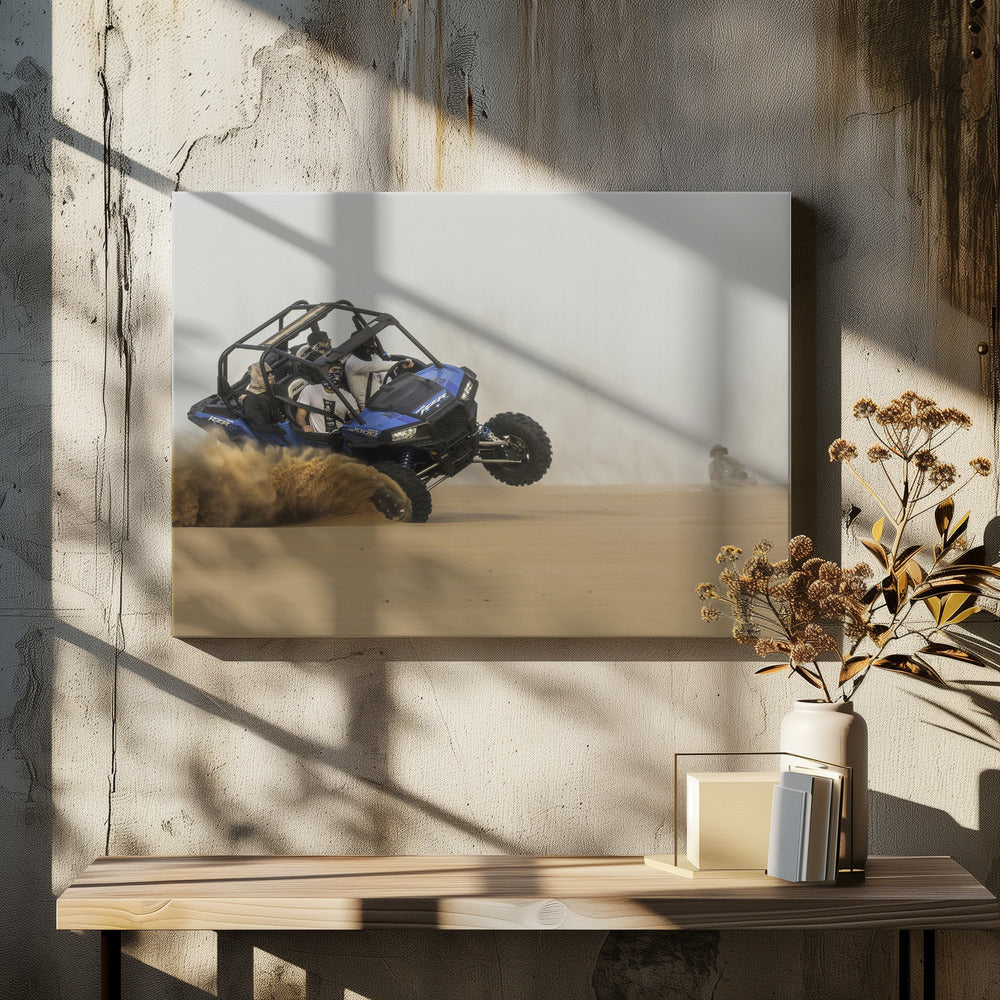 A framed action shot of a blue dune buggy with several passengers making a sharp turn in the desert, kicking up a large cloud of sand and lifting its front wheel off the ground. Wall Art