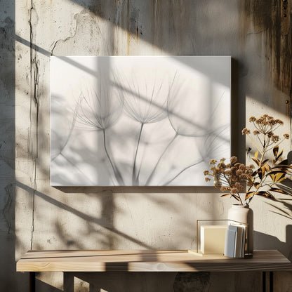 A soft-focus, monochrome macro photograph of several delicate dandelion seeds against a light cream background, presented in a silver frame. Artwork
