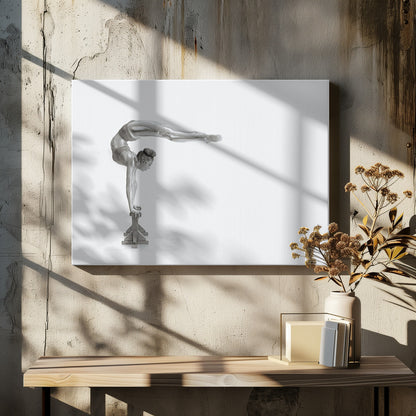 A framed black and white photograph of a female gymnast with a metallic silver-painted body, balancing in a difficult handstand pose on small blocks against a stark white background. Her back is arched and her legs are extended straight out behind her, parallel to the ground. Artwork