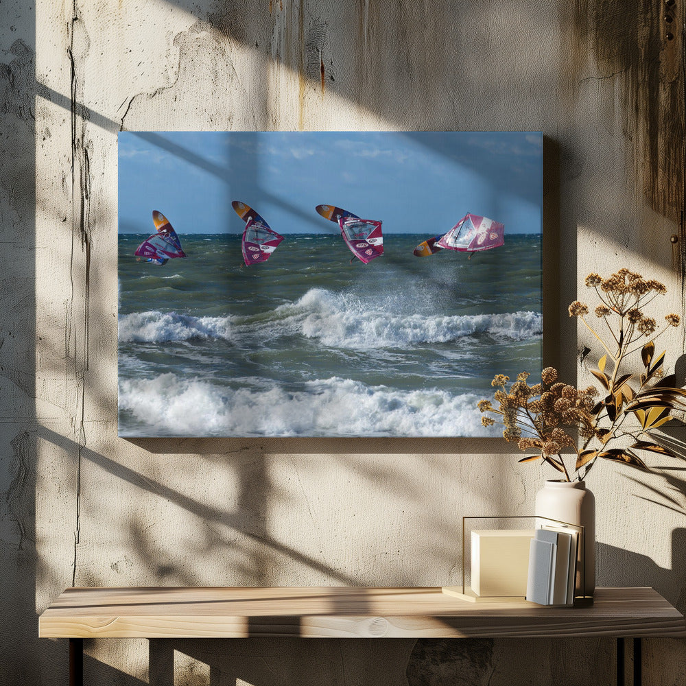 A composite, silver-framed photograph capturing the four stages of a windsurfer's impressive jump over choppy, white-capped ocean waves under a partly cloudy blue sky. Print