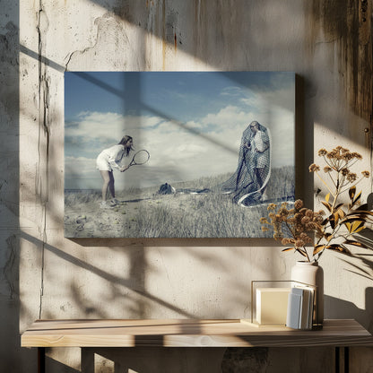 A surreal photograph of two women on a grassy sand dune. One woman is dressed in white tennis attire, bent over and ready to hit a ball with her racket. The other woman stands opposite her, entangled and draped in a large tennis net. The scene is under a cloudy blue sky and has a desaturated, cool-toned color palette, framed in silver. Decor
