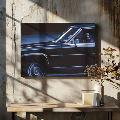 A moody, blue-toned photograph of a Black man sitting pensively in the driver's seat of a dark vintage sedan at night, framed in silver. Poster