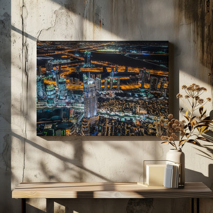 An aerial nighttime photograph of a sprawling modern city, possibly Dubai, with brightly lit skyscrapers and a complex network of illuminated highways creating a vibrant contrast against the dark landscape, all enclosed in a silver frame. Decor