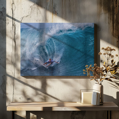 A dramatic action shot of a professional surfer skillfully navigating the inside of a massive, curling blue ocean wave, surrounded by white sea spray, all enclosed in a silver frame. Artwork