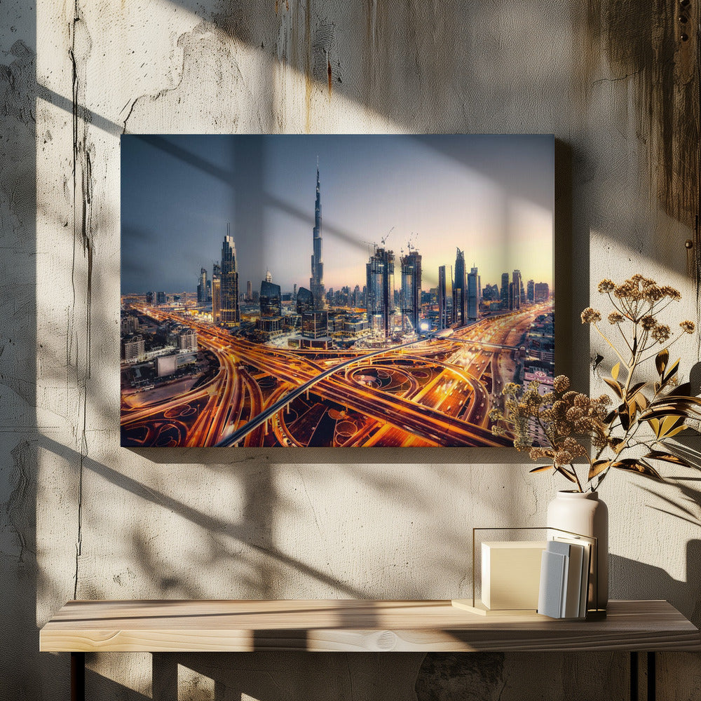 A wide-angle, elevated photograph of the Dubai skyline at dusk, with the iconic Burj Khalifa towering in the center. In the foreground, a complex network of highways glows with the orange light trails of moving traffic, while the city's numerous skyscrapers are illuminated against a twilight sky. Print