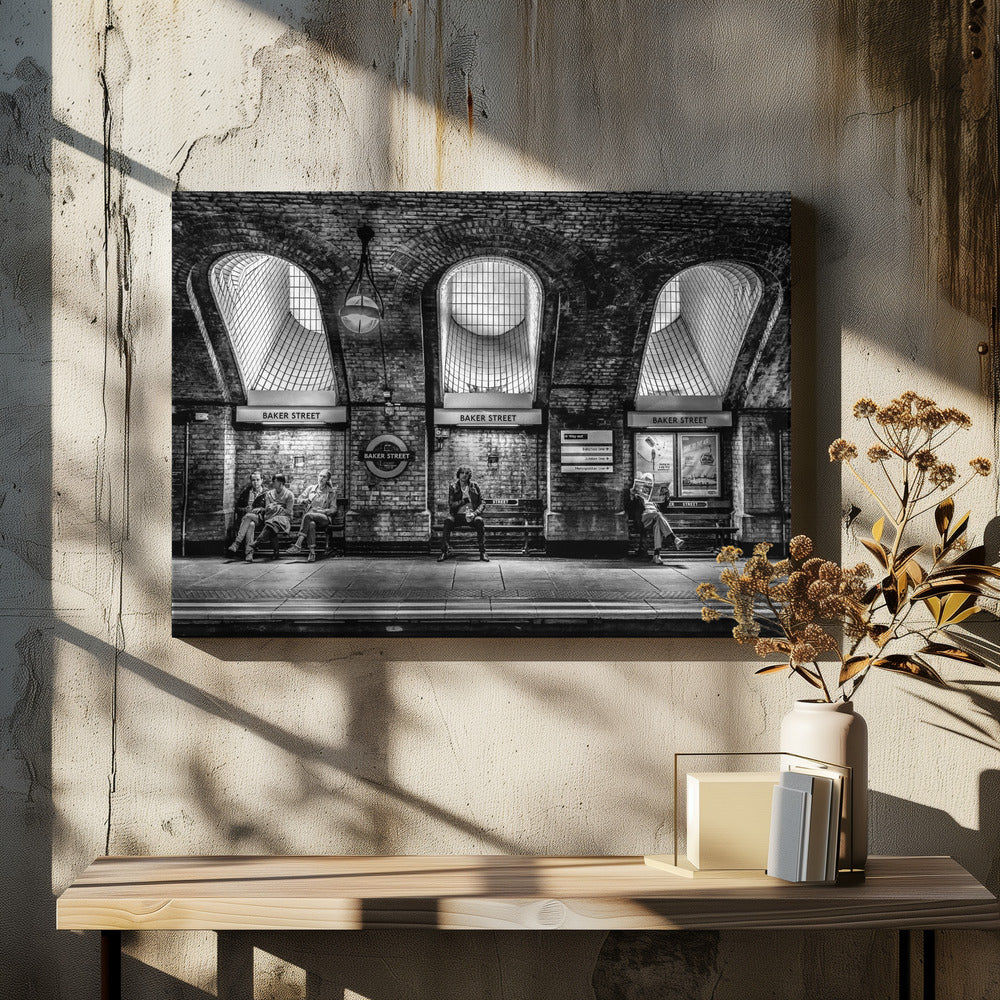 A framed, dramatic black and white photograph of the Baker Street underground station platform in London. Passengers wait on benches beneath iconic brick arches and large grated windows, with signs for 'Baker Street' and the London Underground roundel clearly visible. Print