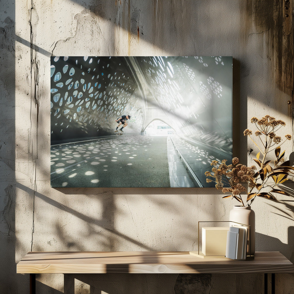 A skateboarder is captured mid-air performing a trick inside a futuristic, metallic tunnel with patterned cutouts that cast dappled light and shadows across the scene, all enclosed within a silver frame. Artwork