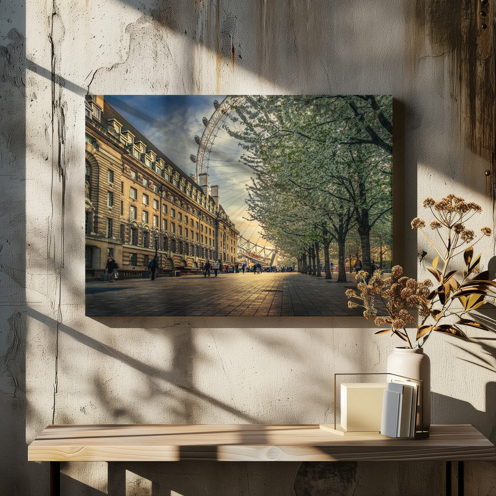 A scenic view of London's South Bank at sunset, with the London Eye visible in the background, a grand historic building on the left, and a row of white blossoming trees lining the sunlit promenade on the right. Wall Art