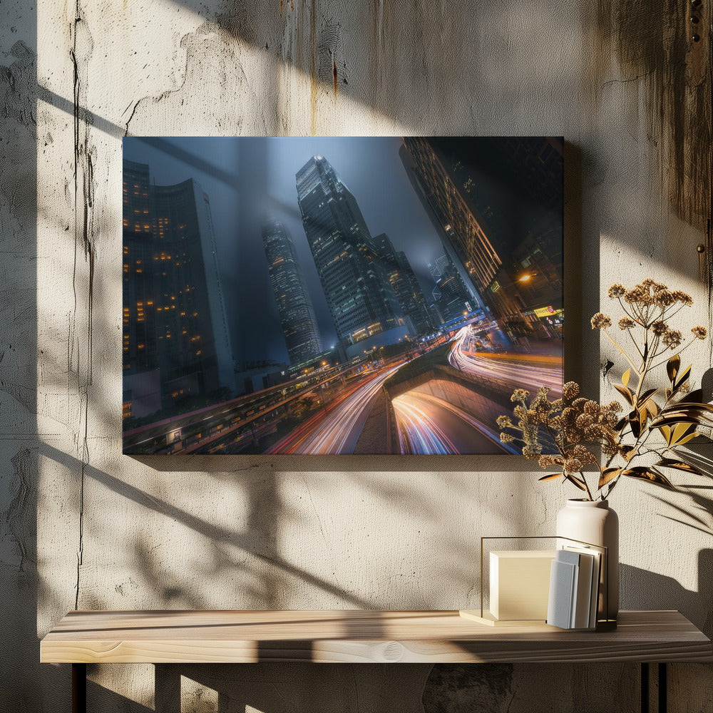 A framed, low-angle photograph capturing a bustling city at night, with towering skyscrapers shrouded in fog. Long-exposure creates vibrant streaks of light from traffic on a multi-level highway, illuminating the dark, modern urban landscape. Wall Art