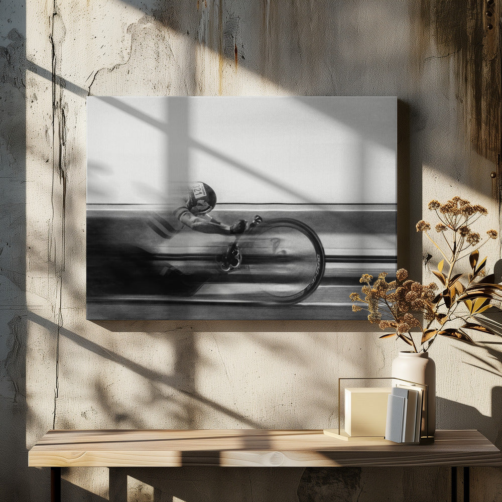 A black and white photograph captured with motion blur, showing a cyclist in an aerodynamic position racing at high speed. The background is blurred into horizontal lines, emphasizing the velocity. The image is enclosed in a silver frame. Wall Art