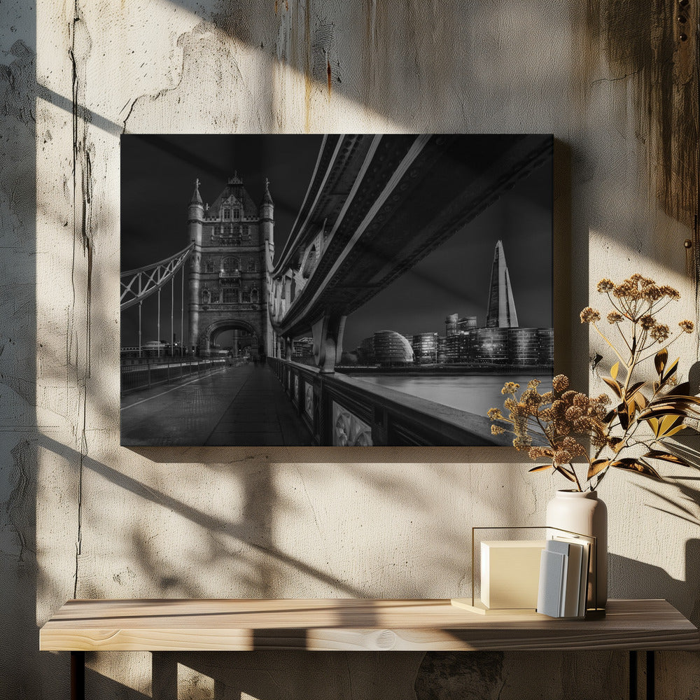 A dramatic, low-angle black and white photograph of London's Tower Bridge at night, taken from the pedestrian walkway. The image showcases the architectural details of the bridge and the illuminated modern city skyline, including The Shard, across the River Thames. Print