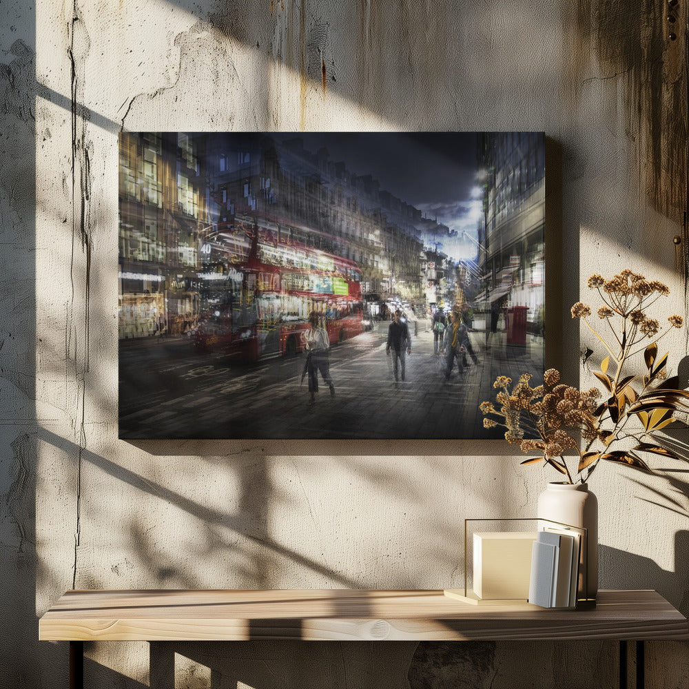 A long-exposure, artistic photograph of a busy London street at night. The motion of a red double-decker bus and pedestrians creates a blurred, ghost-like effect, capturing the vibrant energy of the city. The scene is illuminated by streetlights and building windows, all set within a silver frame. Artwork