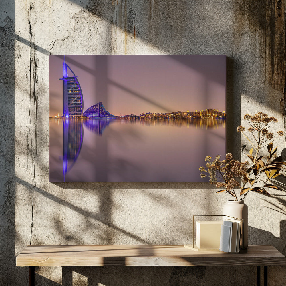 A framed panoramic night photograph of the Dubai skyline featuring the Burj Al Arab hotel lit up in brilliant purple. The city lights and architecture are perfectly reflected in the calm water in the foreground, all under a hazy, dusky sky. Poster
