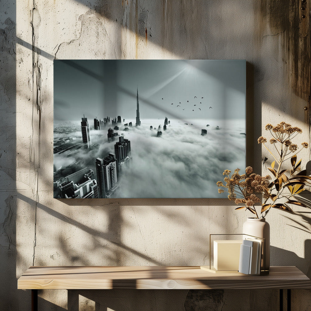 A framed, black and white aerial photograph of the Dubai skyline piercing through a thick layer of clouds. The Burj Khalifa stands prominently in the center, with other skyscrapers emerging from the fog. A flock of birds flies in the sky as a bright sunbeam shines down from the upper right corner. Wall Art