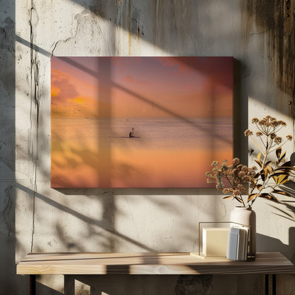A serene photograph of a lone kayaker silhouetted against a vast expanse of calm water during a hazy, golden sunset. The sky and water are bathed in warm hues of orange, pink, and purple. A flock of birds flies in the distance, and the faint outline of a city skyline is visible on the horizon. Wall Art