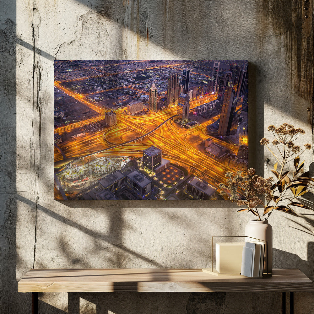 A stunning aerial view of a futuristic city at night, with brilliantly lit highways forming intricate patterns of golden light amidst towering skyscrapers, enclosed in a silver frame. Poster
