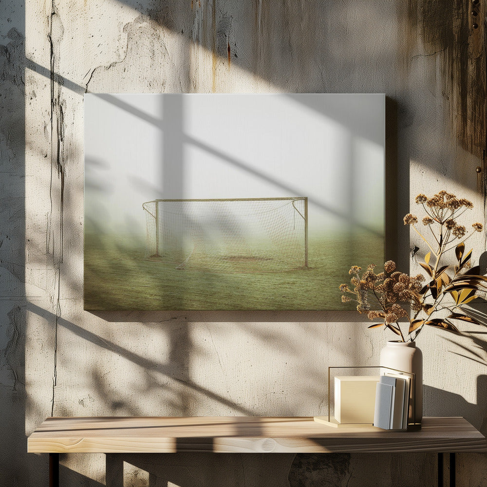A framed photograph of an empty soccer goal with a net, standing alone on a green grass field enveloped in thick, white fog, creating a minimalist and atmospheric scene. Poster