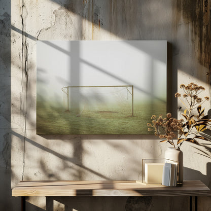 A framed photograph of an empty soccer goal with a net, standing alone on a green grass field enveloped in thick, white fog, creating a minimalist and atmospheric scene. Poster