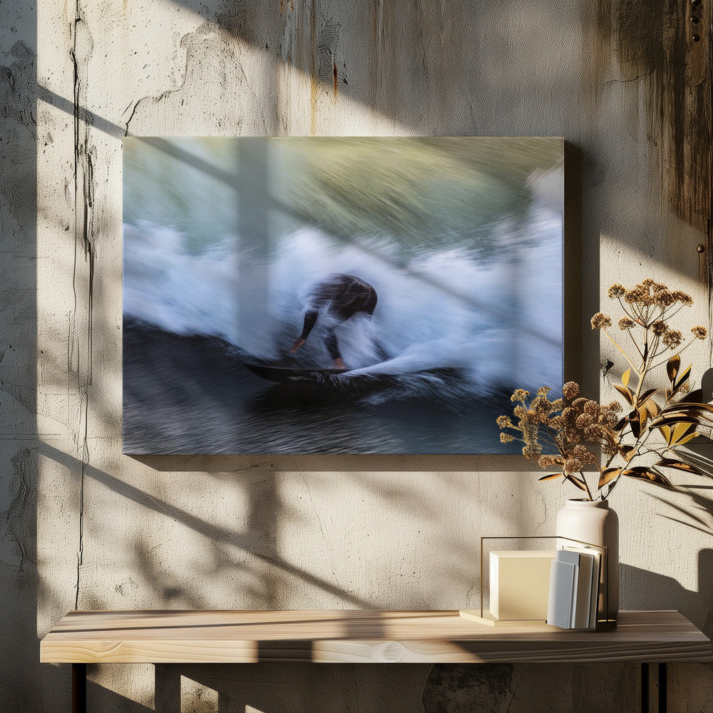 An abstract, motion-blur photograph of a surfer in a black wetsuit, crouched on their board and surrounded by a dynamic swirl of white sea spray and dark blue water, all enclosed in a silver frame. Artwork
