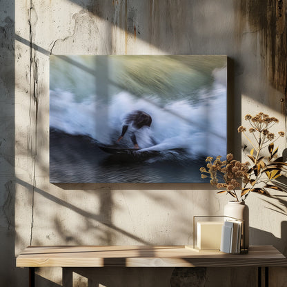 An abstract, motion-blur photograph of a surfer in a black wetsuit, crouched on their board and surrounded by a dynamic swirl of white sea spray and dark blue water, all enclosed in a silver frame. Artwork