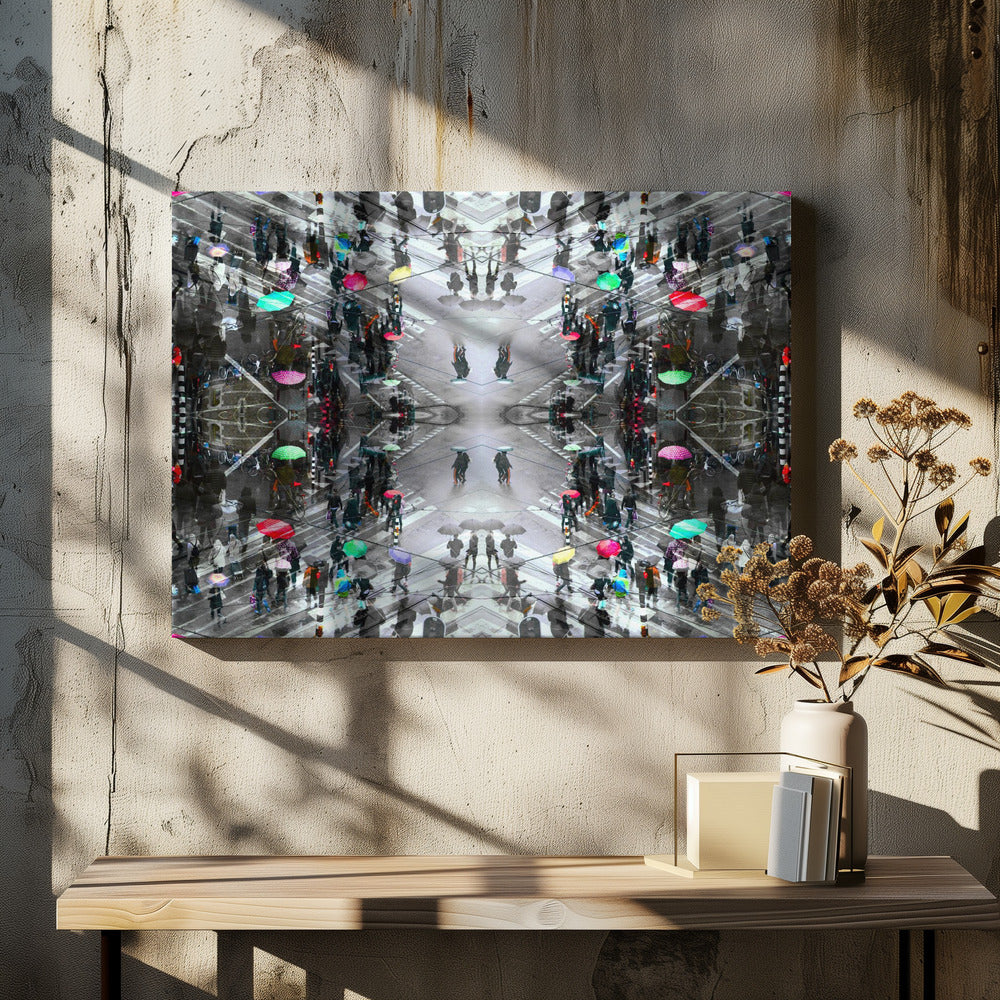 A symmetrical, kaleidoscopic abstract artwork created from an aerial view of a rainy city intersection. The mostly black and white image features pops of vibrant color from numerous umbrellas held by pedestrians crossing the street, all framed in a textured silver border. Artwork