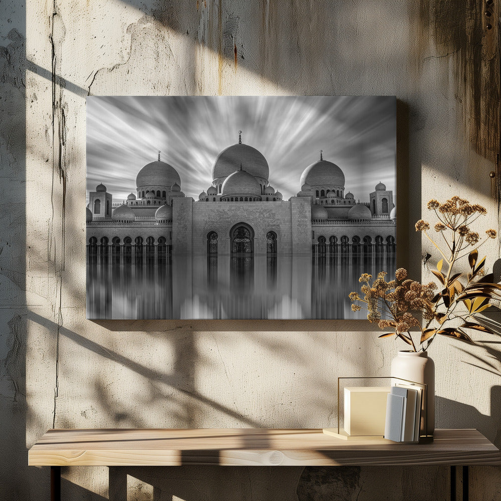 A stunning black and white long-exposure photograph of a grand mosque with multiple domes, reflected perfectly in calm water. The sky above is dramatic, with clouds streaking outwards, and the image is presented in a silver frame. Decor