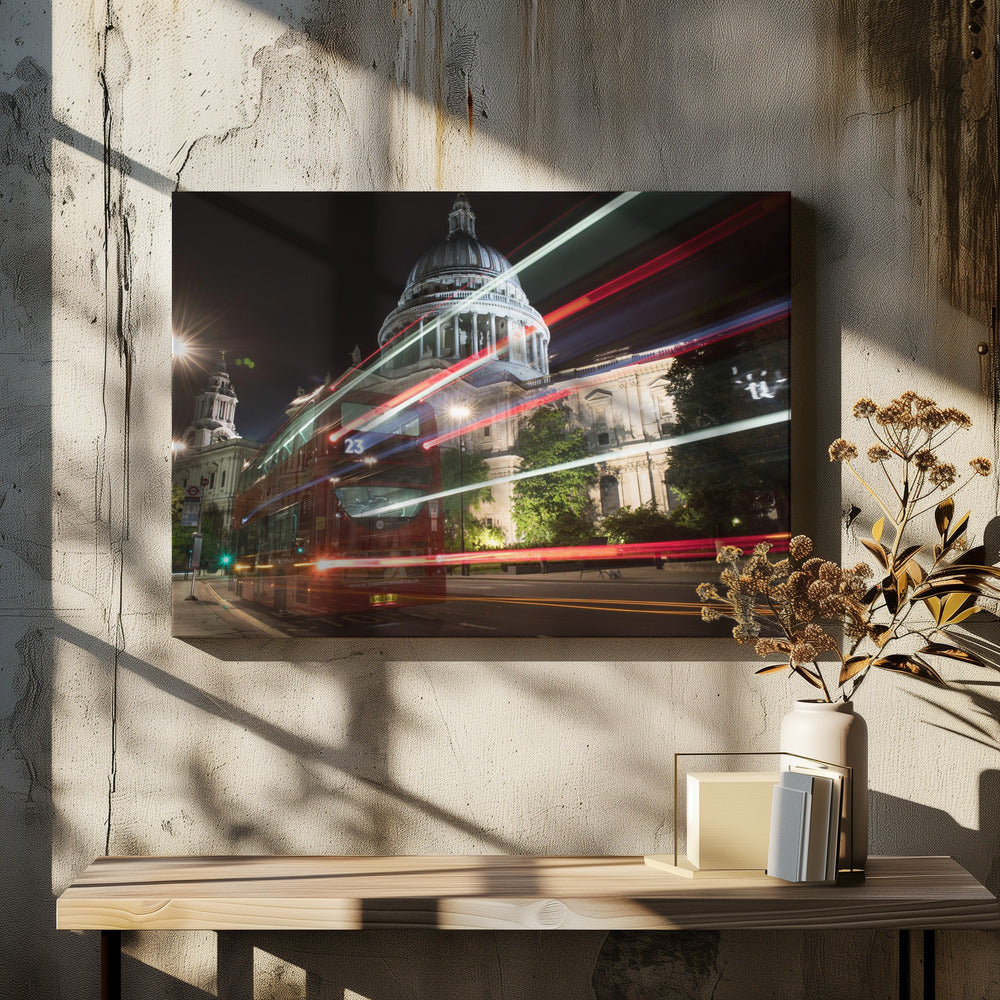 A long-exposure night photograph of a red double-decker bus in London, creating vibrant red and white light trails in front of the illuminated St. Paul's Cathedral. Decor